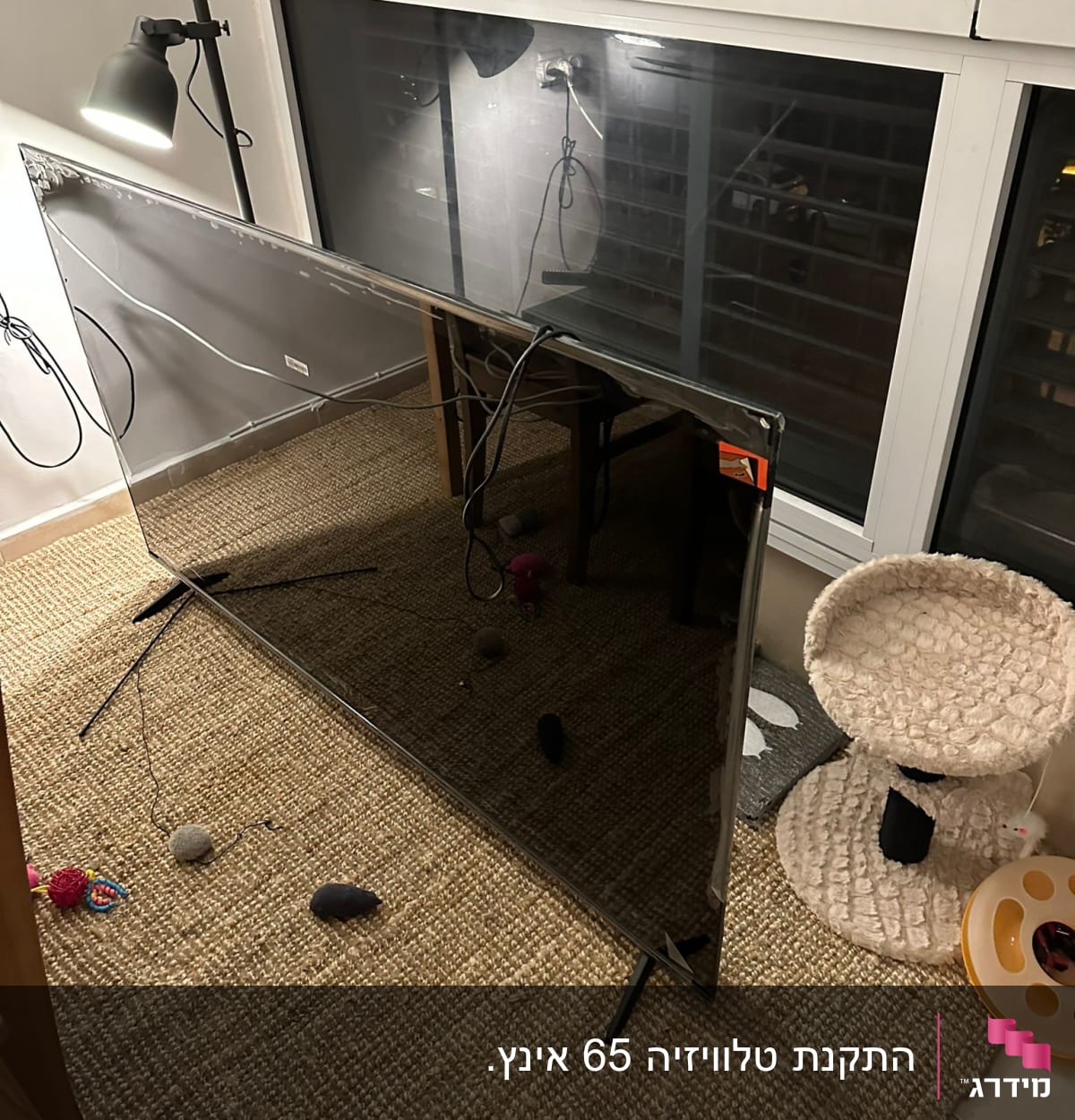 מסך טלוויזיה מונח על שטיח עם כבלים מחוברים